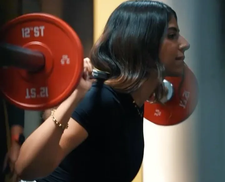 Close view of a squat: red bumper plate and barbell resting on the shoulders